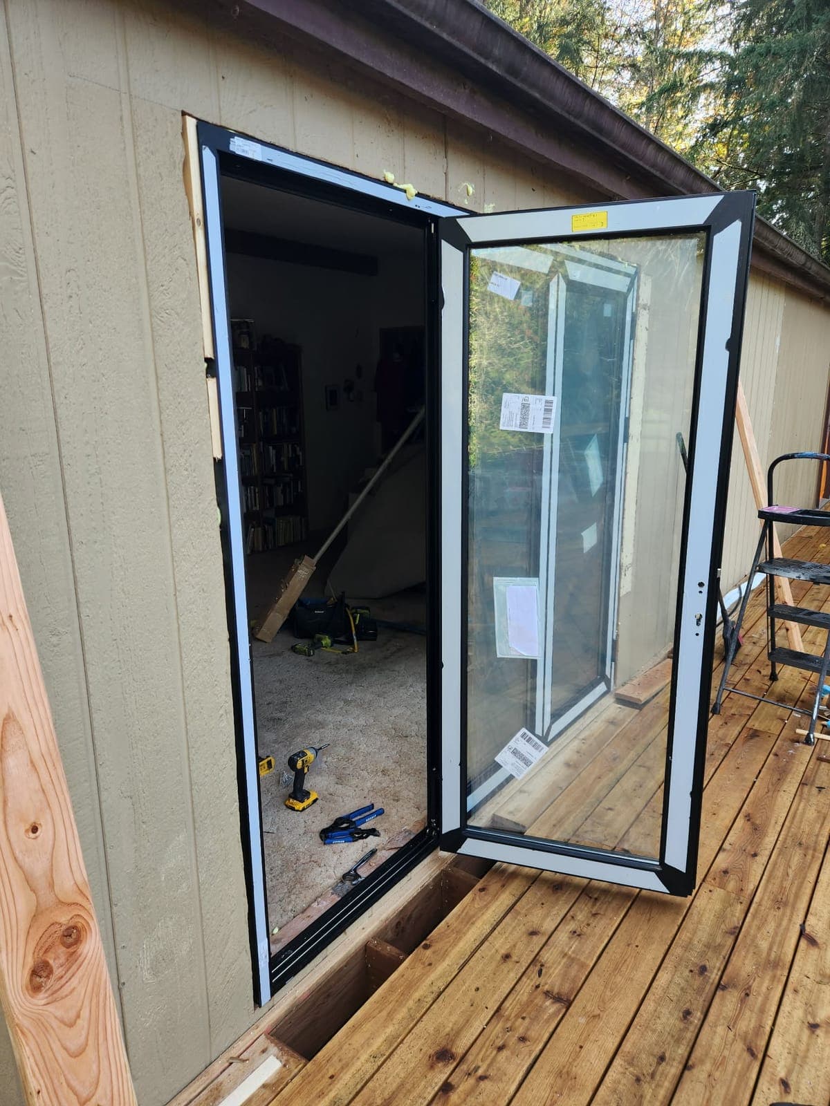Black-framed exterior glass door set in a framed opening, with a wood deck outside